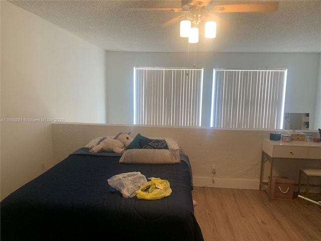 bedroom featuring ceiling fan, a textured ceiling, and light wood-type flooring