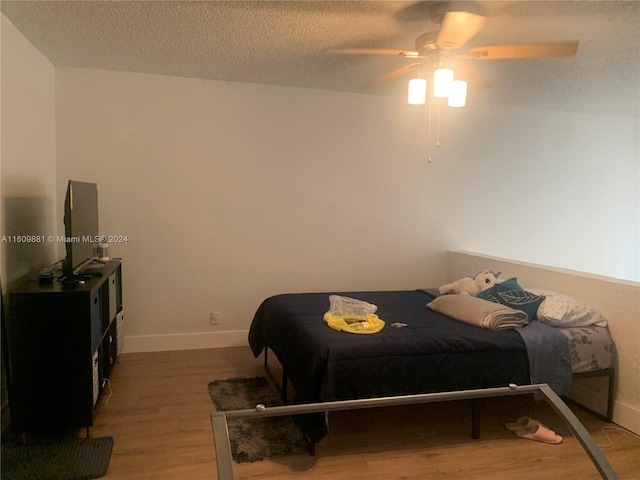 bedroom with ceiling fan, a textured ceiling, and hardwood / wood-style flooring