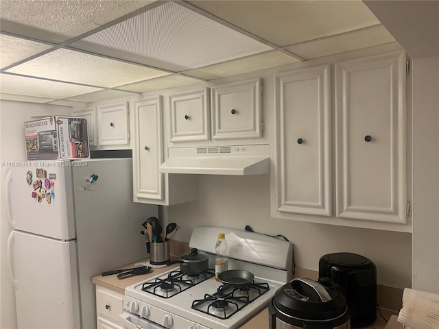 kitchen with white cabinetry, a drop ceiling, and white appliances