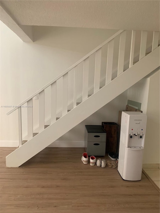 stairway featuring a textured ceiling, wood-type flooring, and a high ceiling