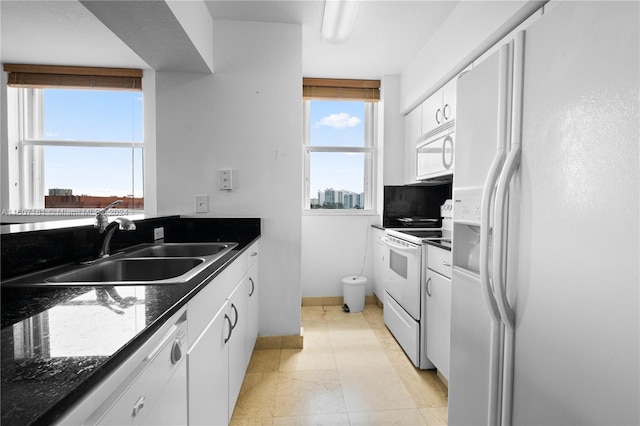 kitchen with white cabinets, sink, white appliances, tasteful backsplash, and dark stone counters