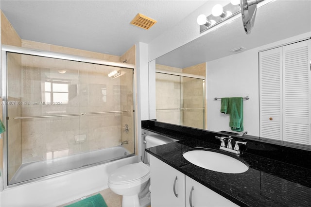 full bathroom featuring a textured ceiling, vanity, toilet, and bath / shower combo with glass door