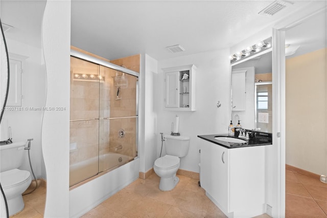 full bathroom featuring tile patterned floors, shower / bath combination with glass door, vanity, and toilet