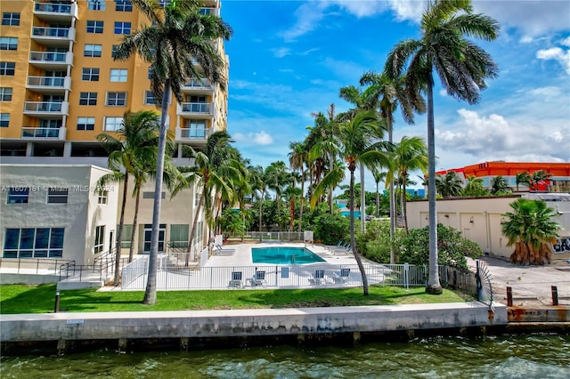 view of swimming pool with a lawn, a water view, and a patio area