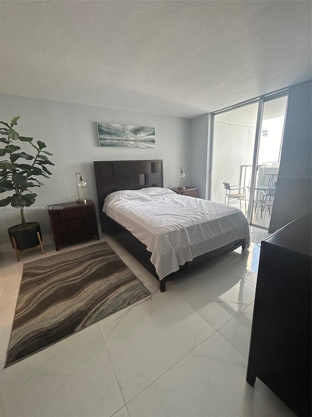 tiled bedroom with floor to ceiling windows, access to outside, and a textured ceiling