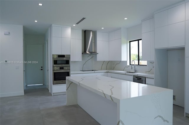 kitchen featuring decorative backsplash, light stone counters, white cabinetry, wall chimney exhaust hood, and a center island