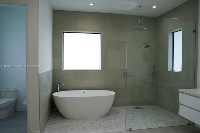 full bathroom featuring toilet, tile patterned flooring, separate shower and tub, vanity, and tile walls