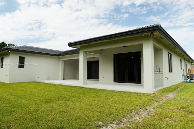 back of house featuring a patio area and a lawn