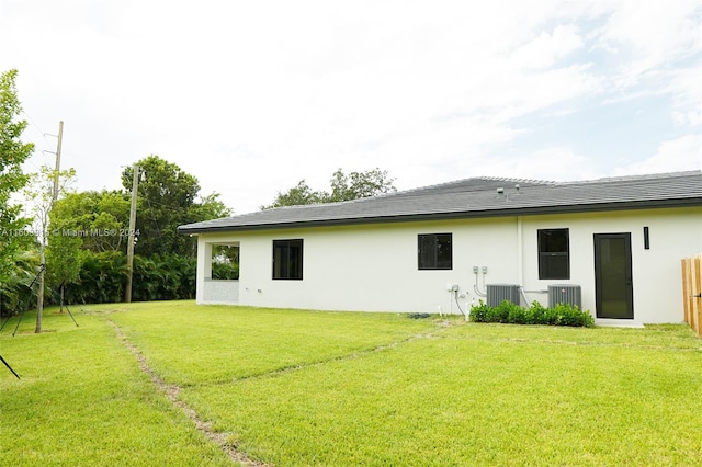 back of property with central AC unit and a lawn