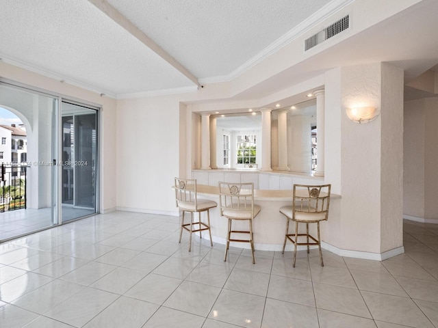 tiled dining space featuring a textured ceiling and crown molding