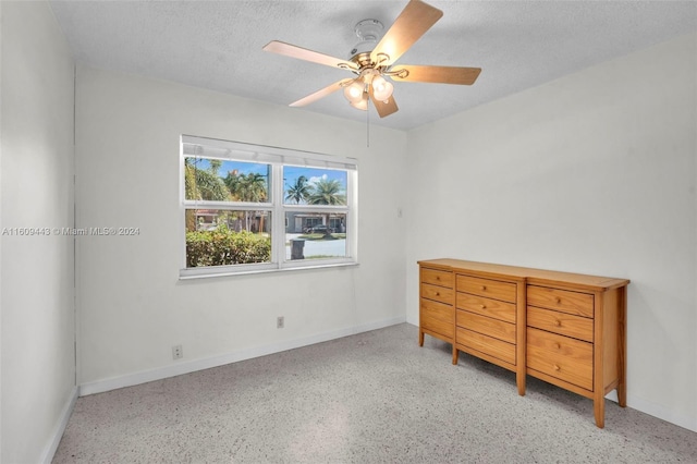 unfurnished bedroom with ceiling fan and a textured ceiling