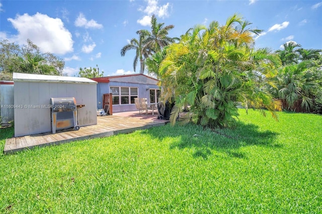 back of property with a wooden deck, a lawn, and an outbuilding