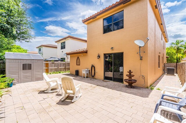 back of property featuring a patio area, central AC, and a storage shed