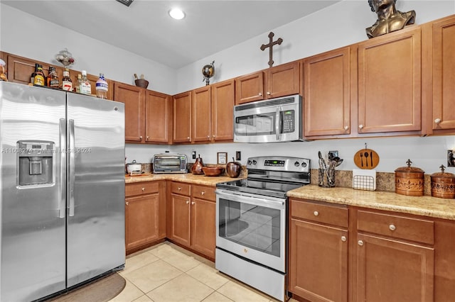 kitchen with light stone countertops, light tile floors, and stainless steel appliances