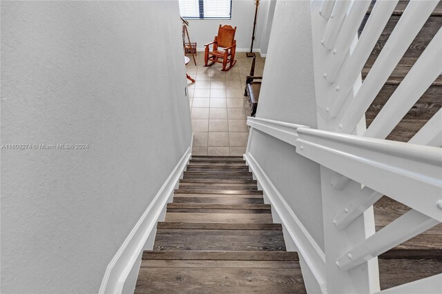 stairs featuring wood-type flooring and tile walls