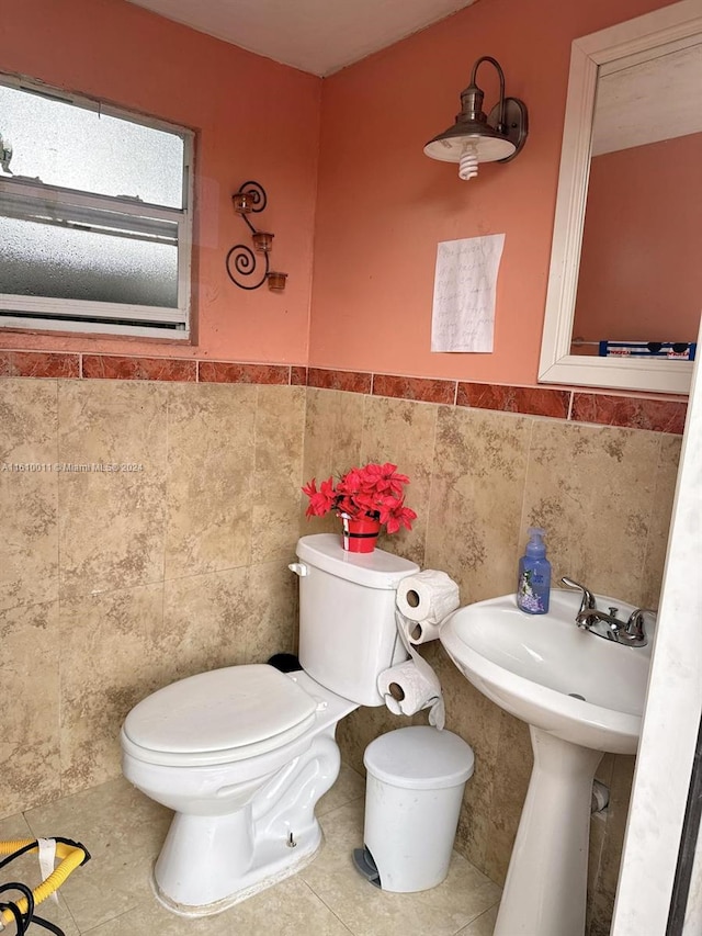 bathroom with toilet, wainscoting, tile walls, and tile patterned floors