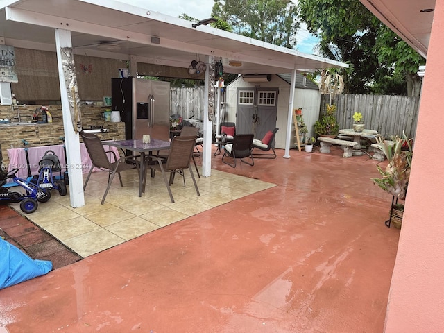 view of patio / terrace with outdoor dining space, a fenced backyard, an outdoor structure, and a shed