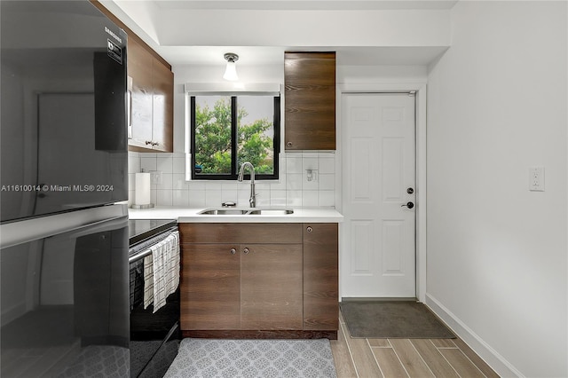 kitchen with black appliances, decorative backsplash, and sink