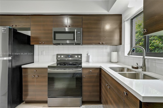 kitchen featuring black refrigerator, dark brown cabinetry, range with electric stovetop, and sink