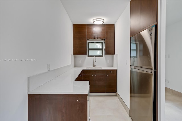 kitchen with dark brown cabinetry, stainless steel fridge, and sink