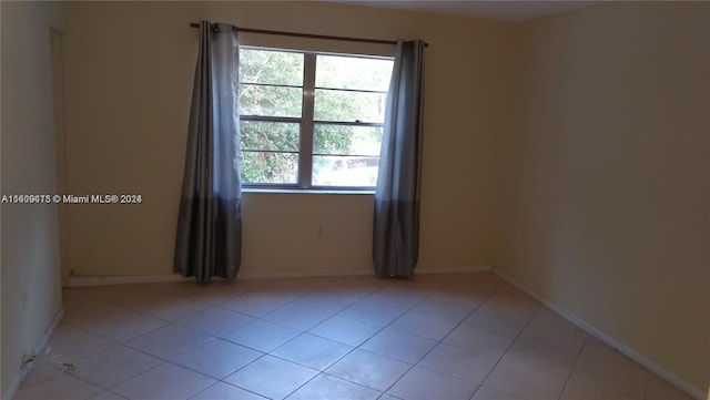 empty room with light tile patterned floors and baseboards