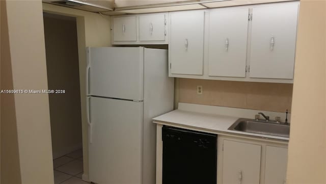 kitchen with black dishwasher, freestanding refrigerator, and white cabinets