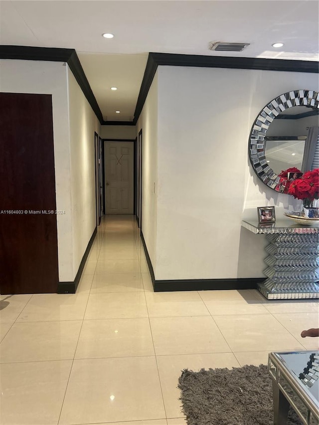 hallway featuring light tile patterned flooring and ornamental molding