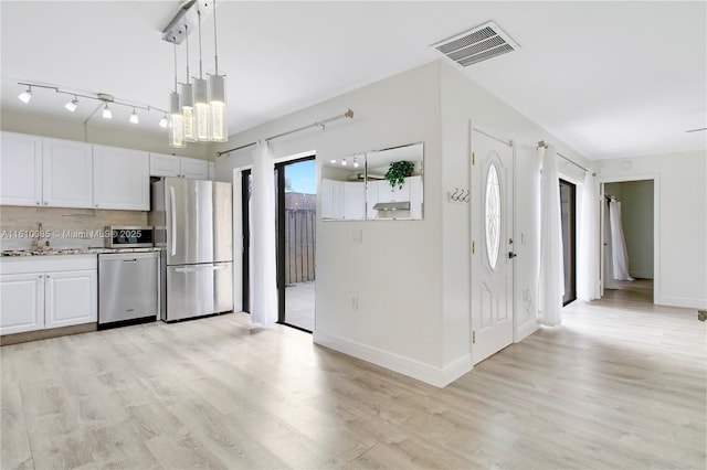 kitchen featuring backsplash, white cabinetry, light wood-type flooring, and appliances with stainless steel finishes