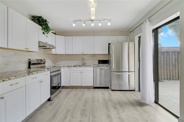 kitchen with white cabinets, light hardwood / wood-style flooring, light stone countertops, appliances with stainless steel finishes, and tasteful backsplash