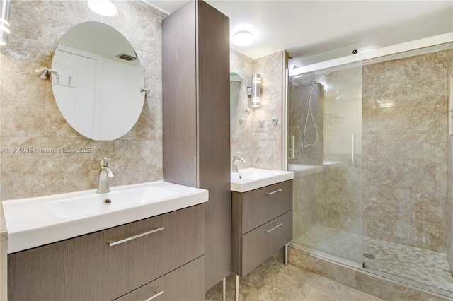 bathroom featuring a shower with door, vanity, and tile walls