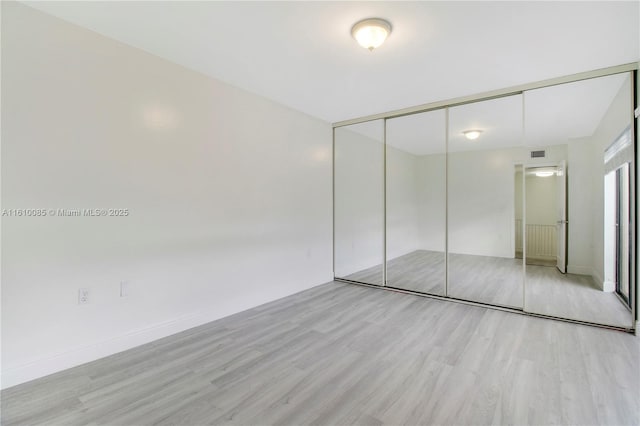 unfurnished bedroom with light hardwood / wood-style floors and a closet