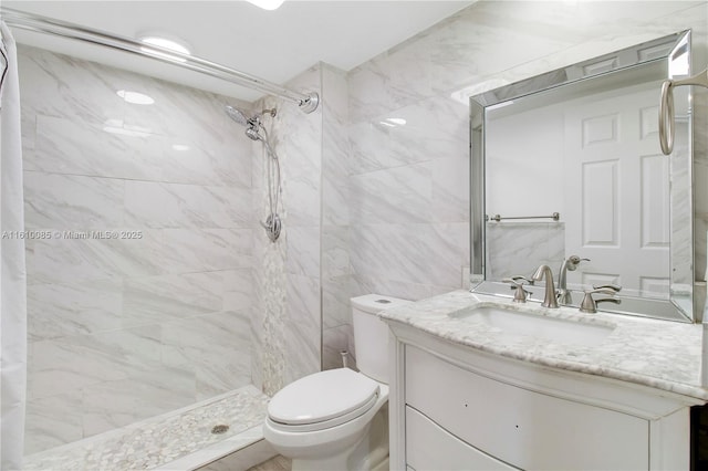 bathroom with a tile shower, vanity, and toilet