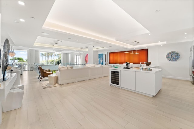 kitchen with a tray ceiling, white cabinetry, wine cooler, and light hardwood / wood-style flooring