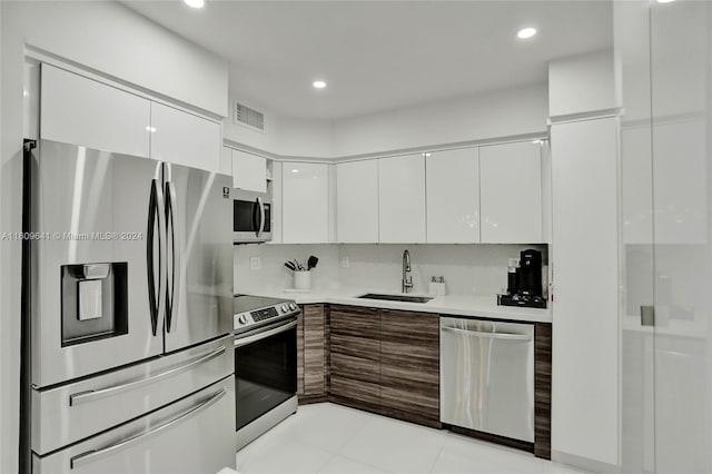 kitchen with light tile patterned flooring, sink, white cabinets, and stainless steel appliances