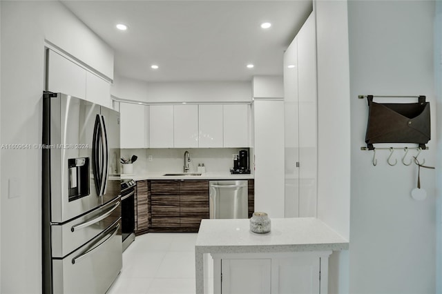 kitchen with sink, light tile patterned floors, tasteful backsplash, white cabinetry, and stainless steel appliances