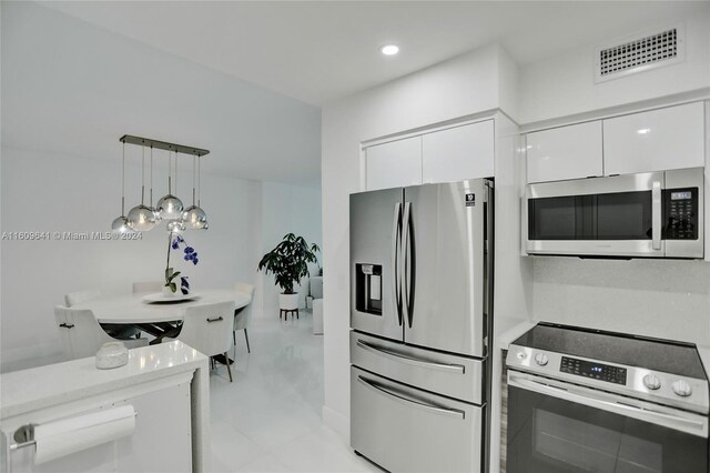 kitchen with white cabinets, appliances with stainless steel finishes, and hanging light fixtures