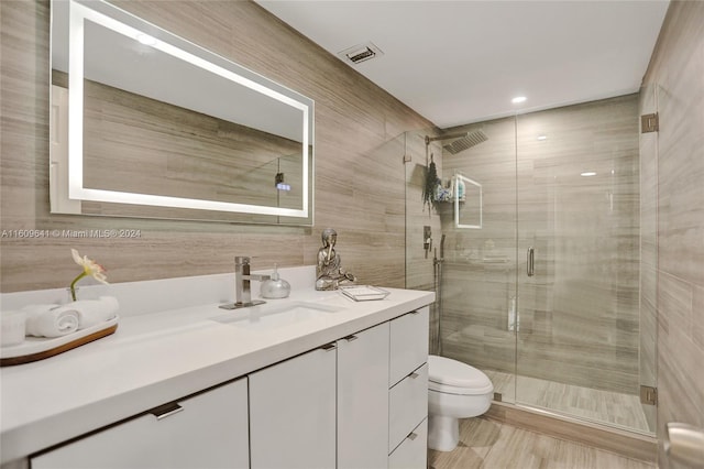 bathroom featuring vanity, toilet, and a shower with shower door