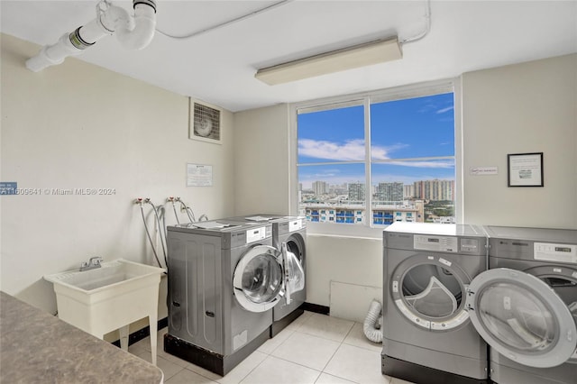 clothes washing area with independent washer and dryer, light tile patterned floors, and sink