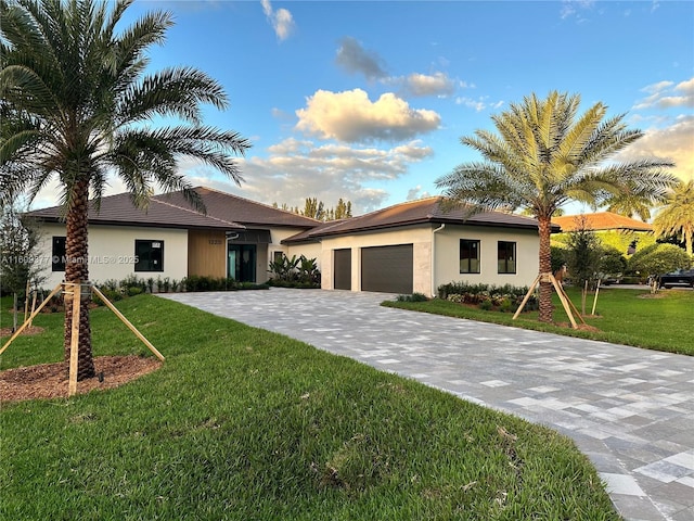 view of front of house with a garage, decorative driveway, a front lawn, and stucco siding