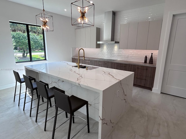 kitchen with a sink, wall chimney exhaust hood, modern cabinets, backsplash, and a large island