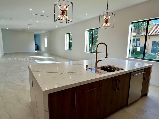 kitchen with light stone countertops, a kitchen island with sink, sink, decorative light fixtures, and dishwasher