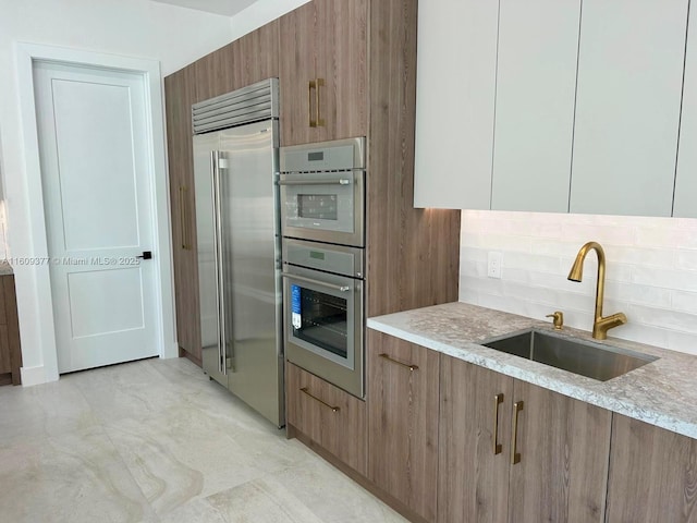 kitchen with backsplash, white cabinetry, sink, and stainless steel appliances