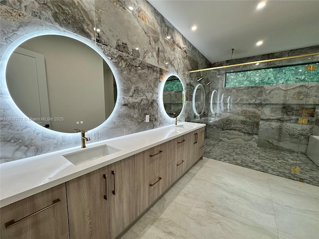 bathroom with a tile shower, vanity, and tile walls