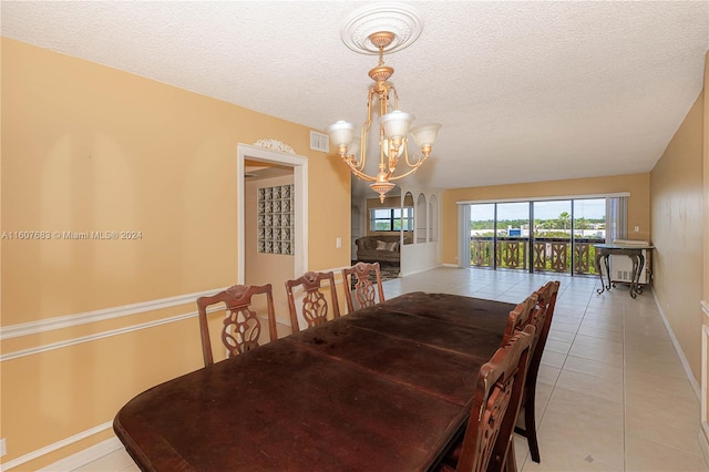 tiled dining space featuring a notable chandelier and a textured ceiling