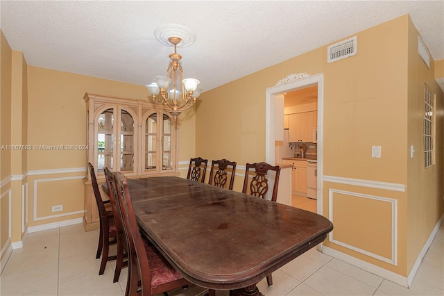 tiled dining space with a textured ceiling and a chandelier