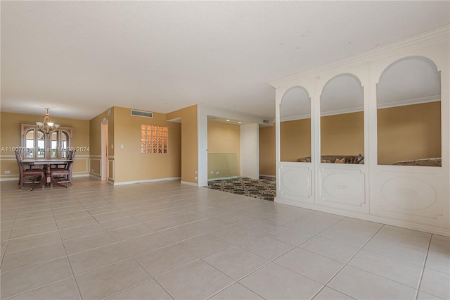 tiled spare room with an inviting chandelier and crown molding