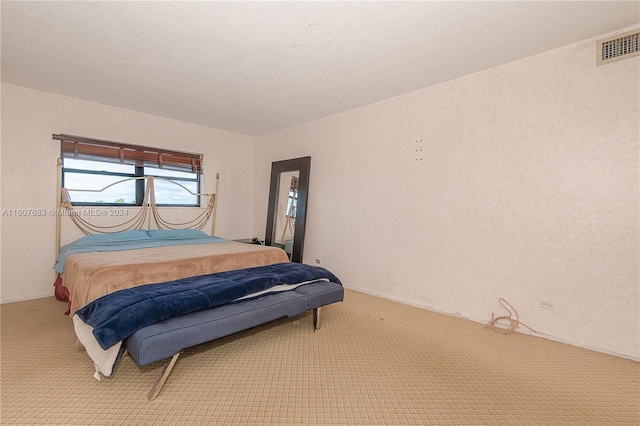 bedroom featuring light carpet and a textured ceiling