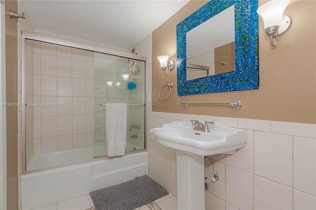 bathroom with tile walls, tile patterned flooring, and bath / shower combo with glass door