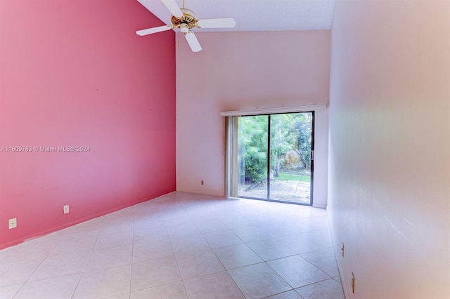 tiled spare room featuring ceiling fan and a high ceiling