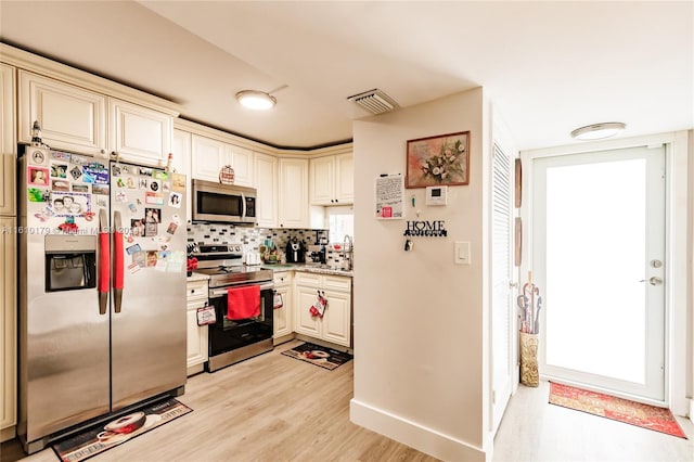 kitchen featuring backsplash, stainless steel appliances, sink, light hardwood / wood-style flooring, and cream cabinetry